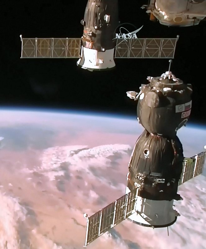 金井宣茂さんらが搭乗し、国際宇宙ステーション（右上）にドッキングするソユーズ宇宙船（NASAテレビより、時事）